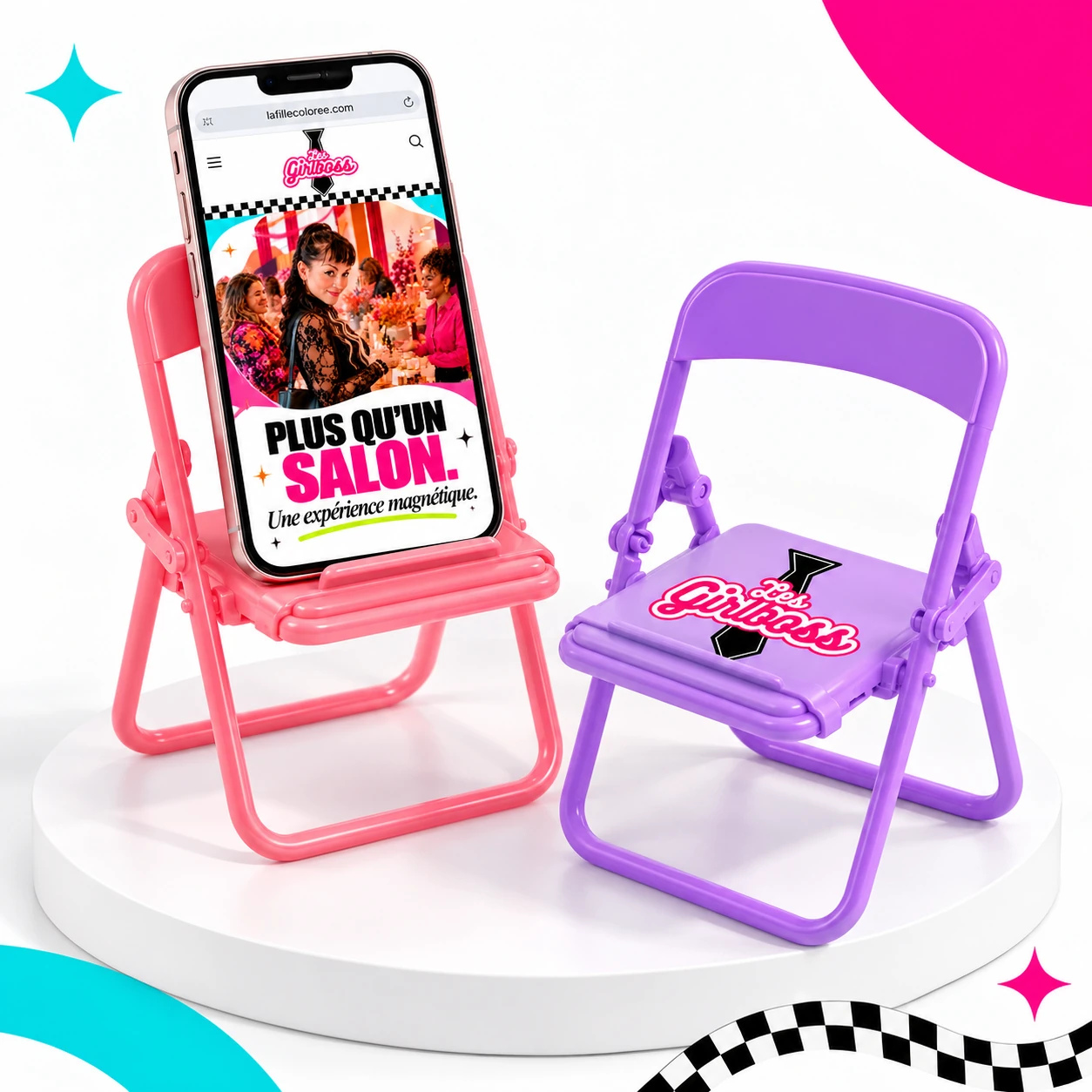 Mini-chaise rose supportant un cellulaire affichant le site Girlboss, et mini-chaise lavande avec le logo sur l’assise